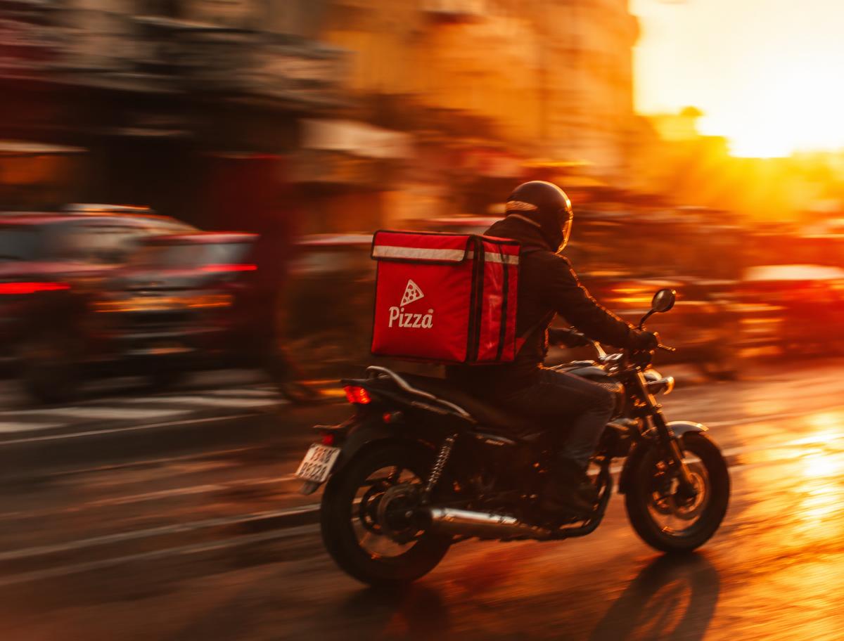 Entregador de pizza em rota ao pôr do sol